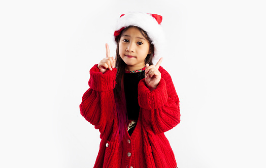 Asian kid in red jacket Christmas theme costume posing smiling finger pointing on white background. Merry Christmas