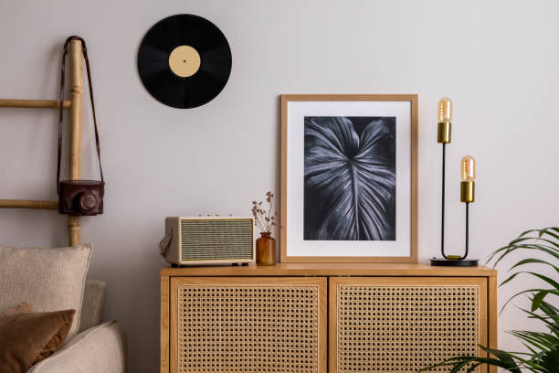 istock Creative composition of living room interior with rattan comode, mock up and personal accessories. Mock up poster. Beige wall. Template. 1439952351