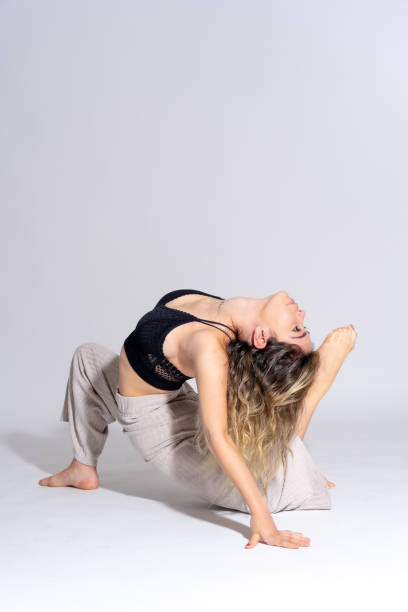 istock Young dancer in a studio photo session with a white background, ballerina, ballet, performing exercises on the floor 1439953901