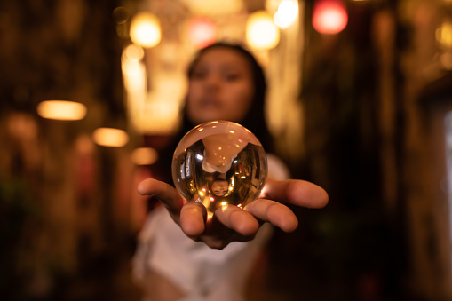 Asian woman holding a crystal ball in the street at night