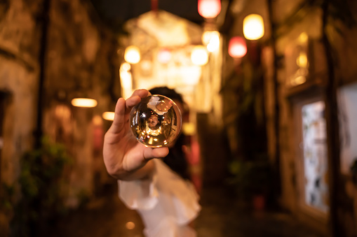 Asian woman showing a crystal ball in the street at night
