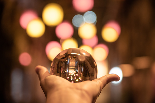 Human hand holding a a crystal ball at night