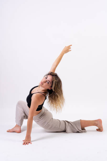 istock Young dancer in studio photo session with a white background, ballet, stretching on the floor 1439954337