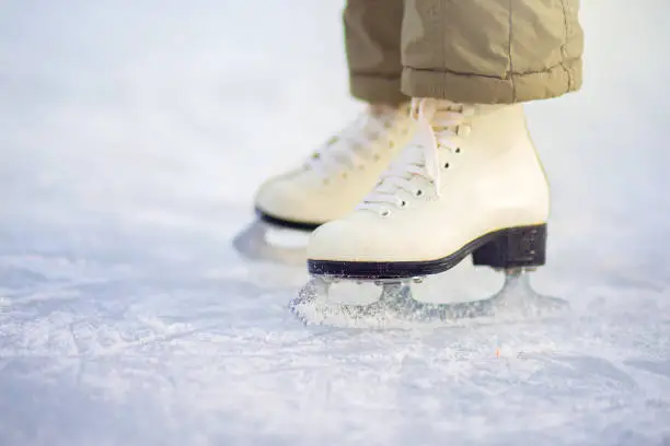 A child in figure skates stands on the ice, closeup skates. Ice skating in winter at the rink