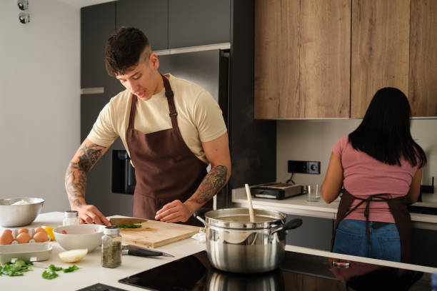 istock Two young latin people cutting coriander and washing dishes at kitchen. 1439957552