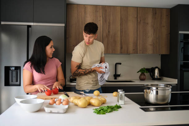 istock Two young latin people talking about a recipe while cooking together. 1439957637