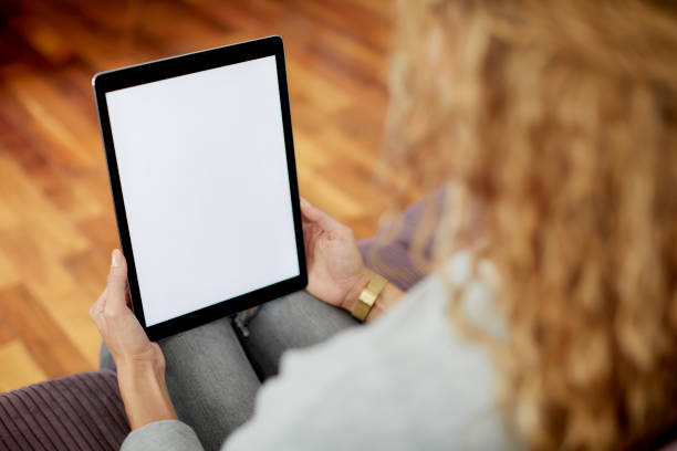 istock Woman holding tablet PC with blank screen on sofa 1439957751