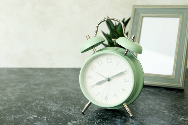 istock Alarm clock, photo frame and succulent on black smokey table 1439960129