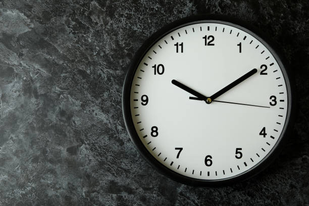 istock Standard black office clock on black smokey background 1439960763