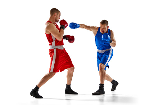 Punch. Two twins brothers, professional boxers in blue and red sportswear boxing isolated on white background. Concept of sport, competition, training, energy. Copy space for ad, text
