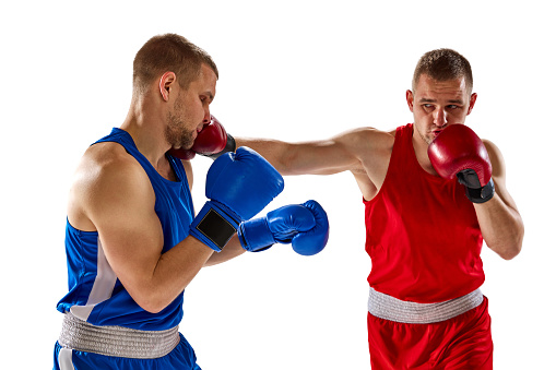 Battle of two boxers. Two muscular professional boxers in blue and red sportswear training isolated on white background. Concept of sport, competition, training, energy. Copy space for ad