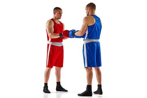 Greetins. Two twins brothers, professional boxers in blue and red sportswear boxing isolated on white background. Concept of sport, competition, training, energy. Copy space for ad, text
