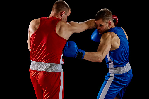 The action takes place on a professional ring with high weight sportsmen.  A sportsman in yellow shorts kicks off the soul of the opponent. All wear unbranded cloth and sport equipment