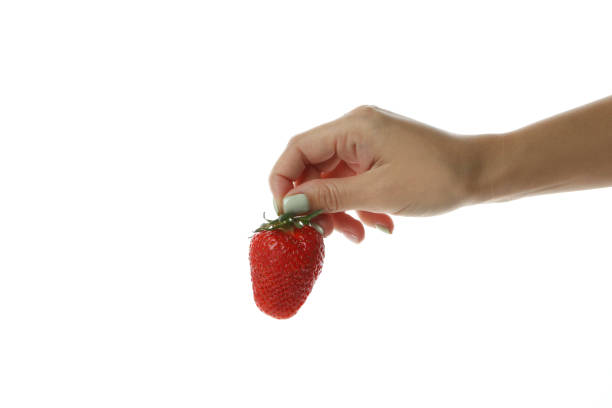 istock Female hand holds fresh strawberry, isolated on white background 1439962862