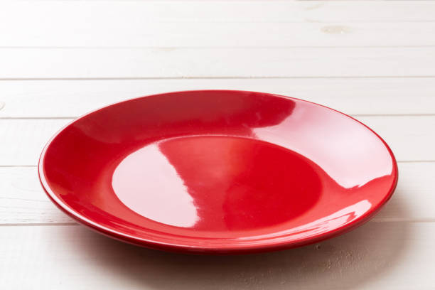 Perspective view of empty red plate on wooden background. Empty space for your design.