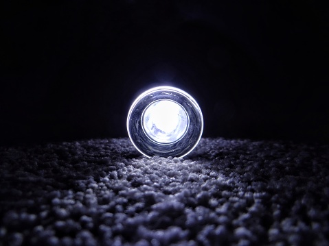 Small torch positioned on a bedroom carpet floor in a dark moody room