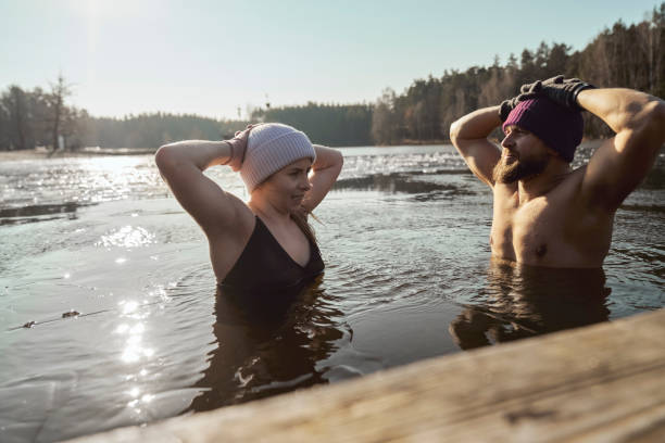 Caucasian couple swimming in frozen lake stock photo