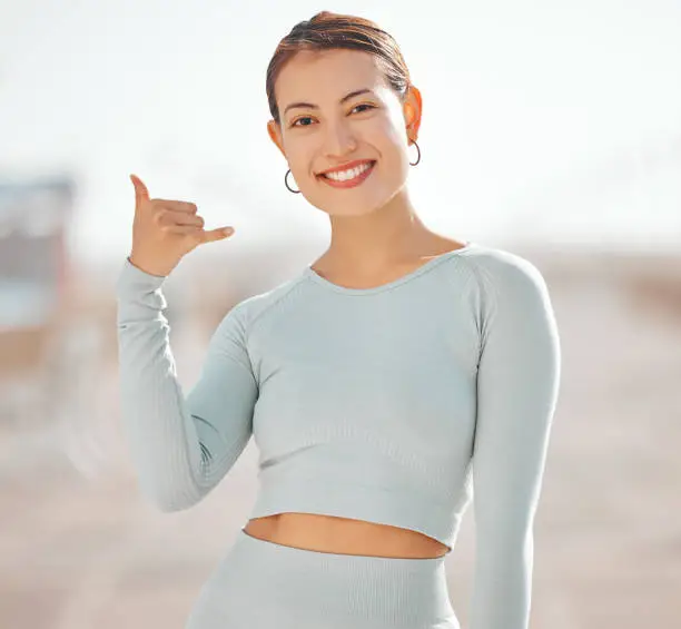 Photo of Woman, portrait and Hawaii surfer hand or flirting call me sign while taking outdoor sports break. Happy, friendly and welcome gesture symbol from popular culture for a young person greeting.