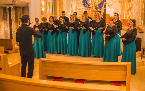 istock A large group of people dressed in the same formal clothes rehearse before a choral performance with a conductor 1439971387