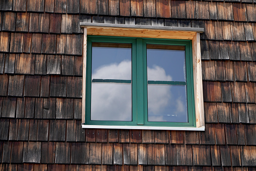 Wall and green window of traditional wooden american wooden cabin viewed from the outside