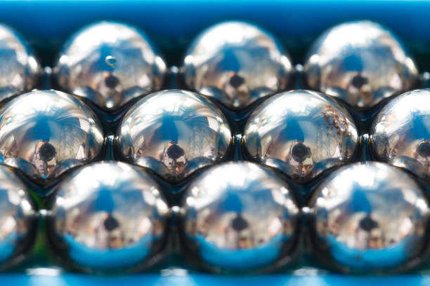 Balls from a ball bearing close-up in a row in oil, with reflections.Macro photo. Abstract background.