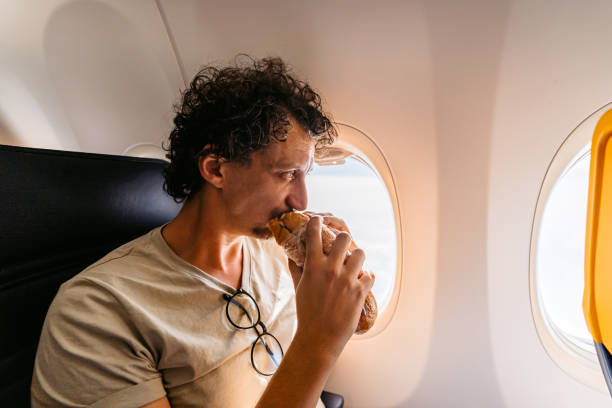 istock Young Man Eating A Sandwich In An Airplane 1439973273