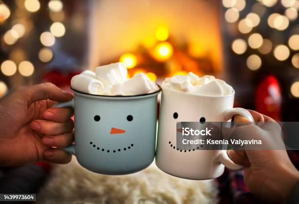 Mom And Child Are Relaxing Together On A Cozy Winter Evening By The Fireplace Closeup Of Two Hands With Snowman Face Cup Of Hot Cocoa With Marshmallows Christmas Holidays Happy Moments At Home Stock Photo - Download Image Now