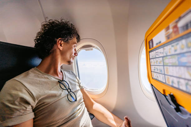 istock Young Man Looking Out The Window Of An Airplane 1439973690