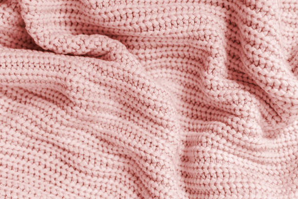 istock Crumpled folded knitted light pink fabric texture background. Soft and warm woven plaid or sweater close-up. Cozy comfort textile backdrop. 1439974222