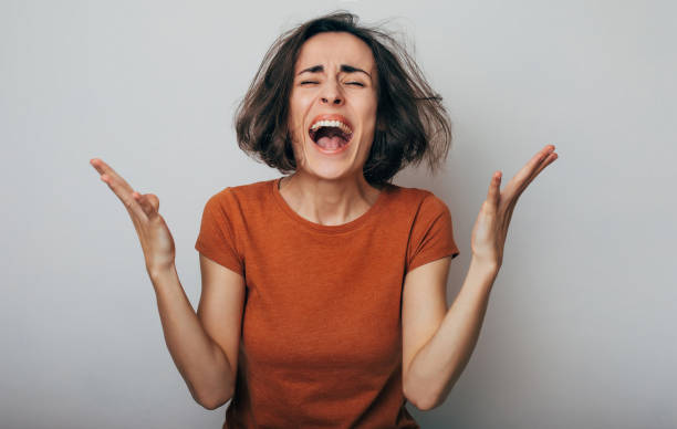 Close up shot of screaming crazy frustrated woman with anxiety, anger and depression. Very upset and emotional woman crying. Young girl with angry and furious face. Human expressions and emotions stock photo