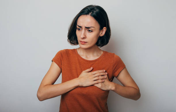 Young woman suffering from heart attack isolated on gray background stock photo