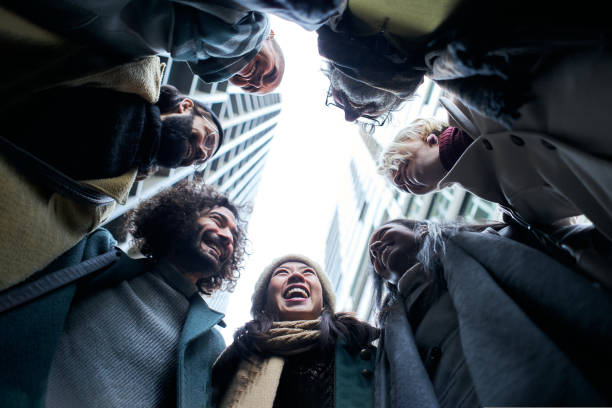 Low angle of a unity group of business people in circle. Happy smiling colleague co-workers. Community of diverse aged and multiracial teamwork. Cheerful teamwork in winter clothes stock photo