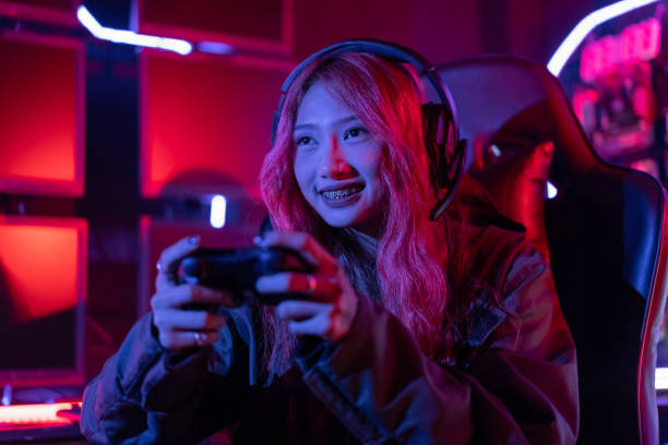 istock You win. Gamer using joystick controller plays online video game with computer neon lights backgrounds, woman use gaming headphones playing live stream esports games console at home. 1439978141