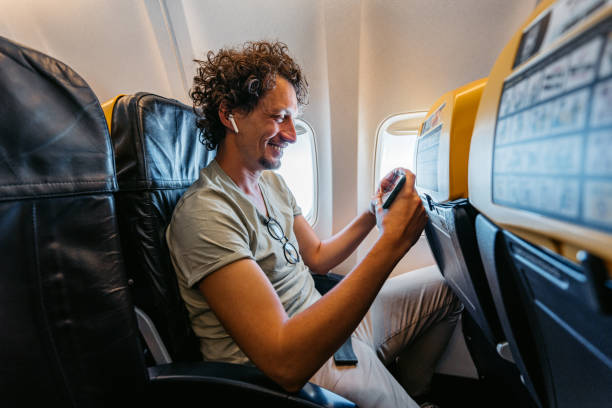 istock Young Man Watching A Funny Video On The Phone In An Airplane 1439979378