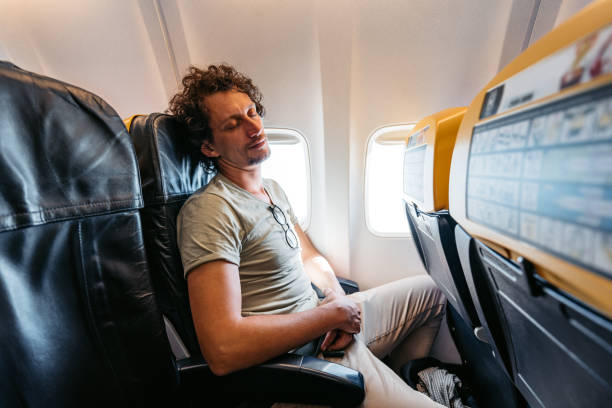 joven durmiendo en un avión - silla al lado de la ventana fotografías e imágenes de stock