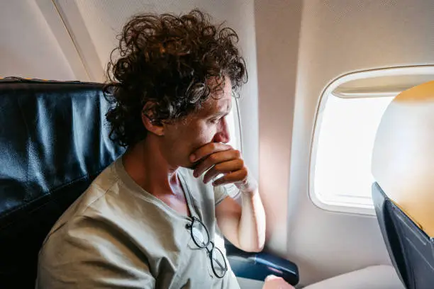 Photo of Scared Male Passenger Looking Out The Window Of An Airplane