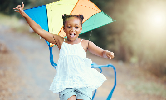Nature, summer and girl with a kite running in a park with a smile. Weekend, happiness and a little black child having outdoor fun. Freedom, development and growth for happy young kid playing outside
