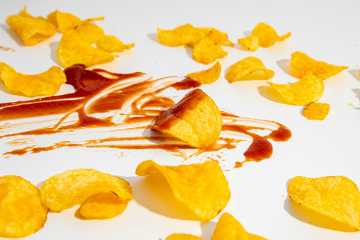 Kutchut is smeared and potato chips are scattered on a white background.