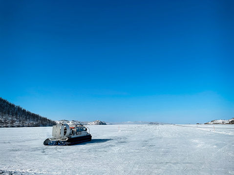 Khivus winter transport on ice. Hovercraft. Ice on the surface of the transparent frozen Lake Baikal. Blue sky. Horizon. Horizontal. Baikal in winter.
