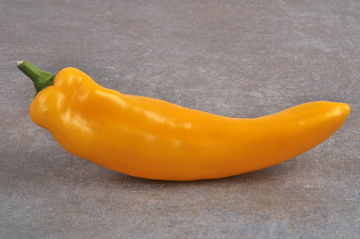Yellow long bell pepper close on gray background