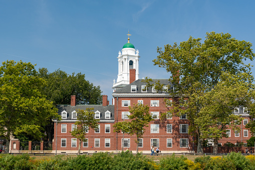 Cambridge, Massachussetts - September 18, 2022 - People stroll and bike past Eliot House, one of the seven original residential houses at Harvard University.