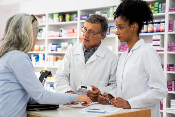 istock Two pharmacists helping a senior female customer with her medication 1439988858