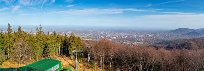 Beautiful panorama seen from Szyndzielnia Mountain. Upper station of cable car and autumn forest in the foreground, Bielsko - Biala and Beskidy Mountains in the background.