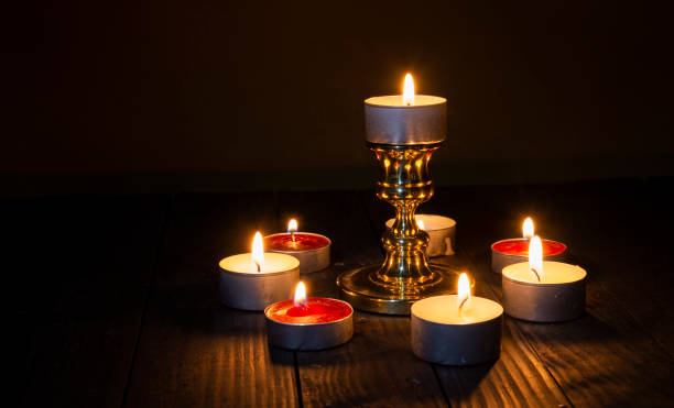 istock Multiple candles light with big stand on wood table dark background 1439998355