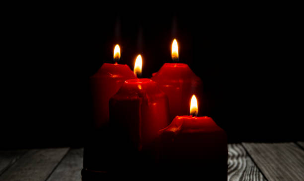 istock Four red candles light on dark room with dark background 1439998366