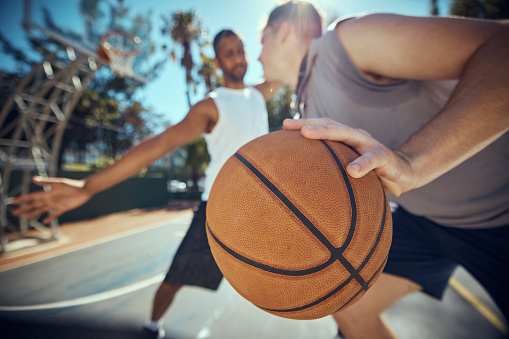 Basketball, competitive sports and practice match with men, players or friends playing a game at an outdoor court. Athletes staying fit and enjoying leisure activity with a ball while trying to score