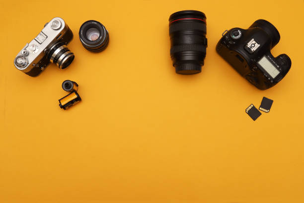 istock Old film camera with accessories and modern digital camera with accessories on orange background. View from above 1440005538
