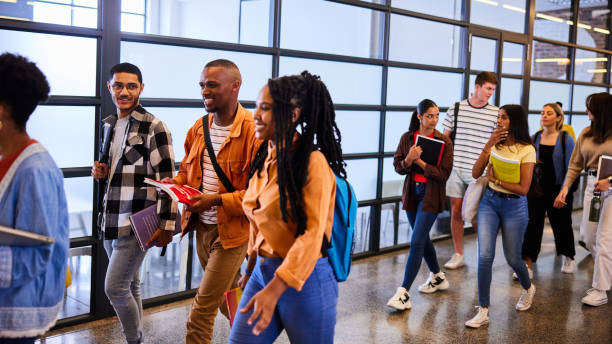 Smiling college students walking together down a hallway at school - fotografia de stock