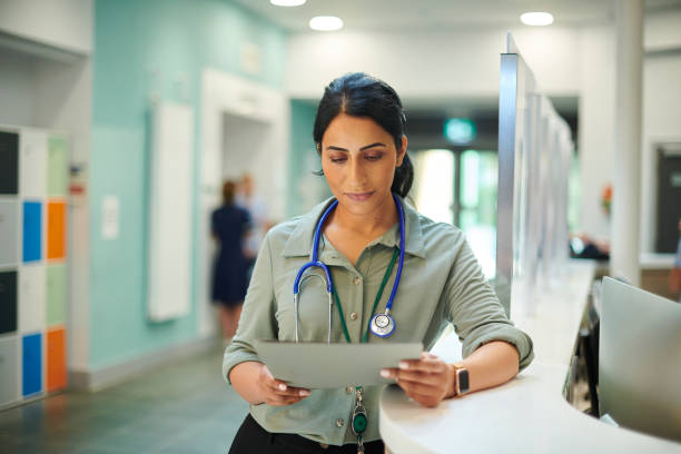 hospital doctor reading medical notes hospital consultant portrait rolled up sleeves stock pictures, royalty-free photos & images