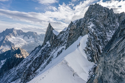 Climbers or alpinist on a knife sharp ridge of an alpine peak or summit of Aiguille du Rochefort. Alpine landscape and adventure climbing ascent.
